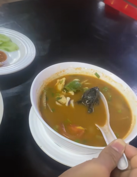 Woman scoops up frog from tom yam soup